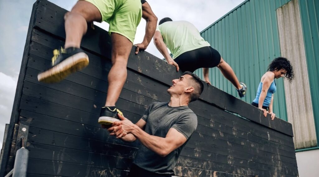 A man helps another man climb over a wall