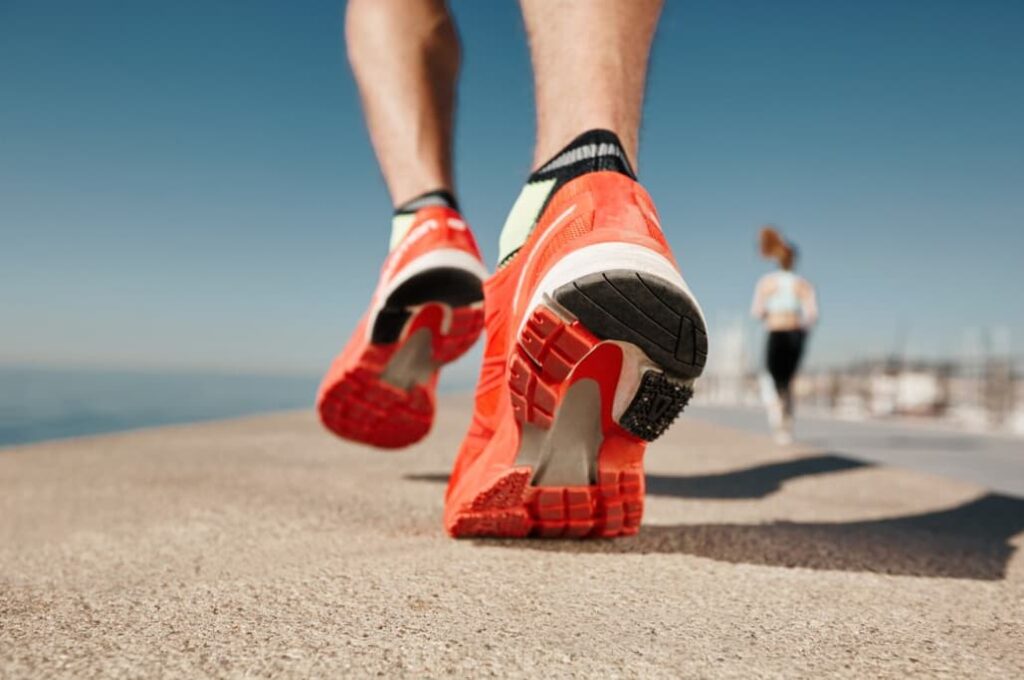 A close-up on a runner's bright red shoes on a seaside path